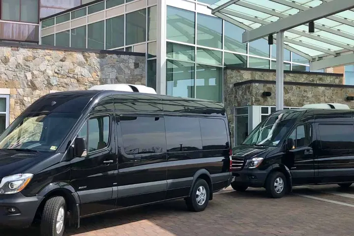 Two Royal Limousine Mercedes-Benz Sprinters staged under a covered entrance